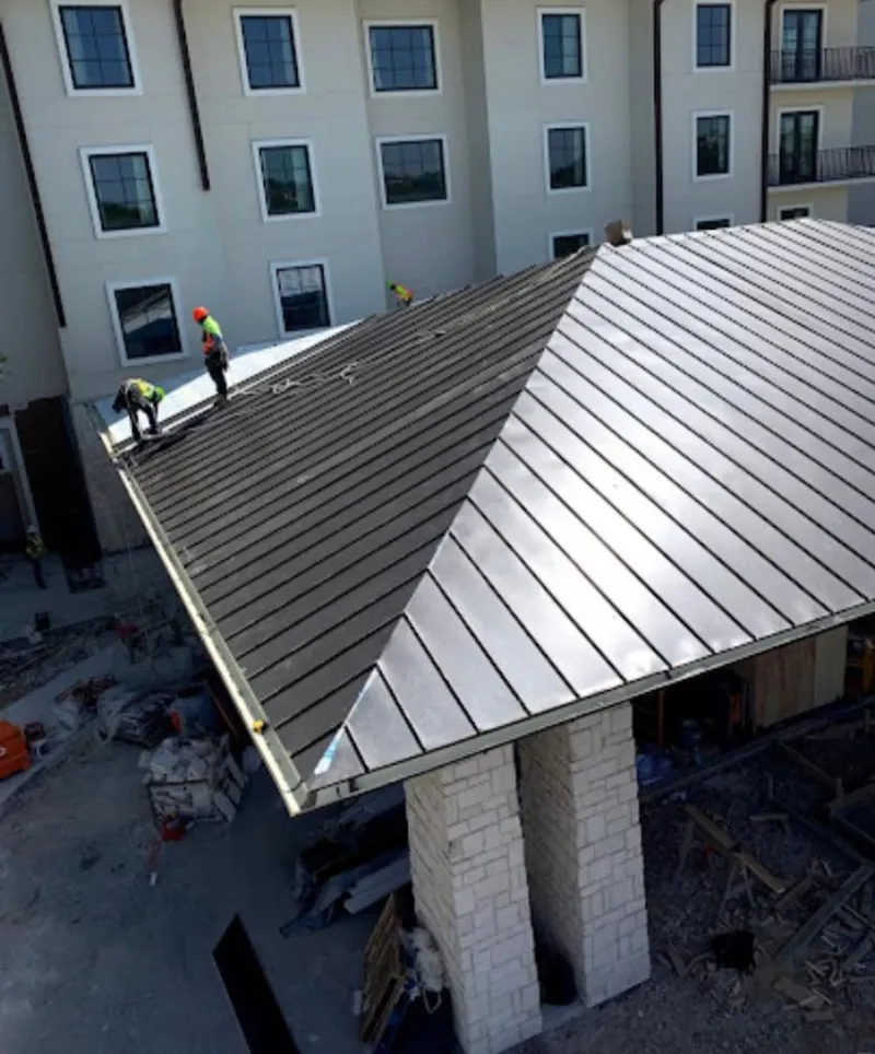 Crew installing standing seam metal roof panels on a commercial project in DeFuniak Springs